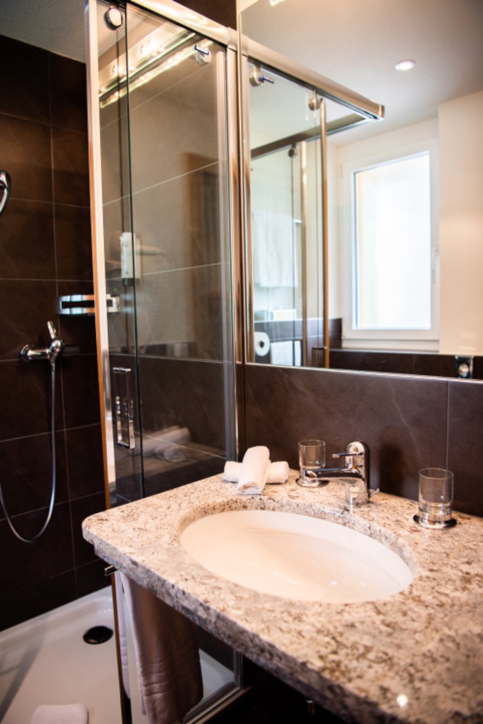A bathroom with a stone basin and a glass shower
