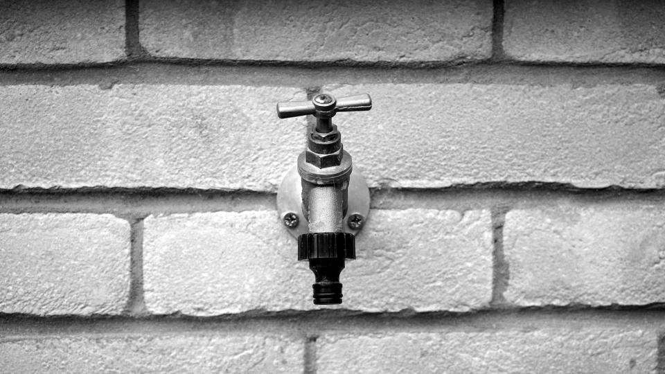 An outdoor tap on a brick wall