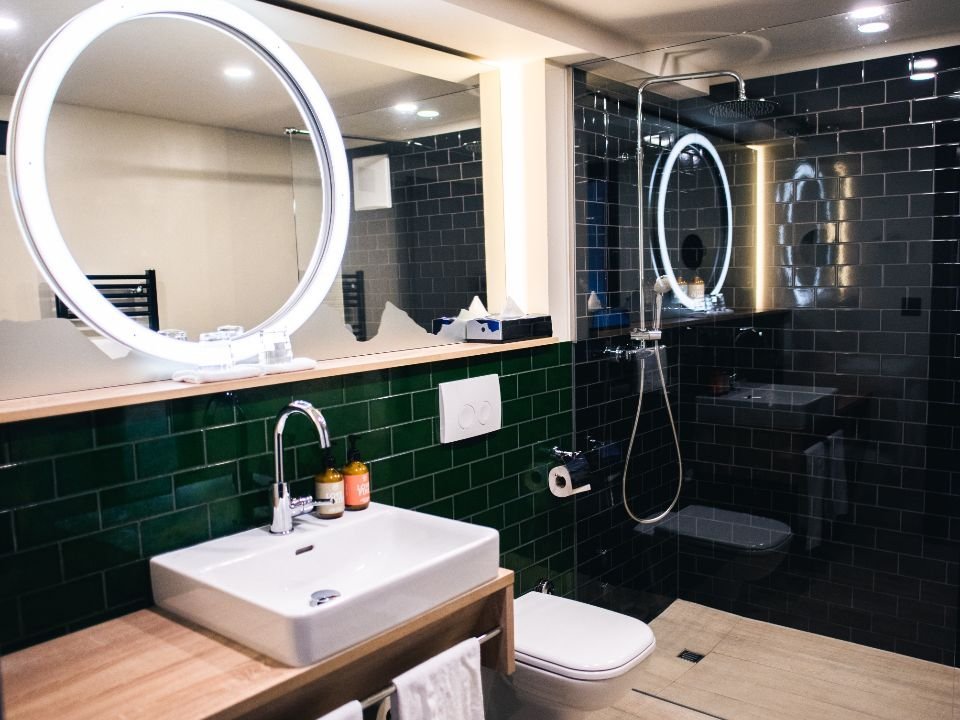 A remodelled bathroom with a round mirror and dark tiles